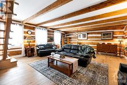 Spacious living room lots of windows, hardwood floor and exposed logs - 