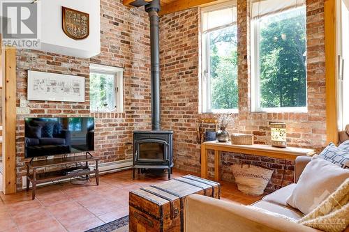 Family room's accent antiqued brick wall and Jotul woodstove - 150 Dewolfe Street, Ottawa, ON - Indoor Photo Showing Living Room With Fireplace