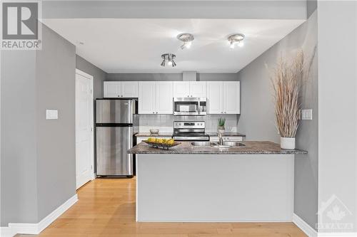 Kitchen includes double sink and breakfast bar seating. - 231 Crestway Drive Unit#J, Ottawa, ON - Indoor Photo Showing Kitchen