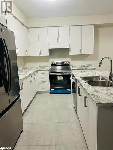 Kitchen with appliances with stainless steel finishes, light stone counters, sink, light tile patterned floors, and white cabinetry - 113 Stern Drive, Welland, ON - Indoor Photo Showing Kitchen With Double Sink