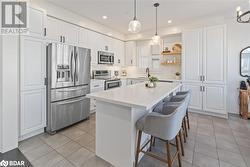 Kitchen featuring white cabinets, a center island, a healthy amount of sunlight, and stainless steel appliances - 