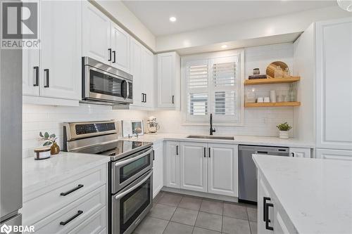 Kitchen featuring tasteful backsplash, light stone counters, stainless steel appliances, sink, and white cabinetry - 19 Mugford Crescent, Brampton, ON - Indoor Photo Showing Kitchen With Upgraded Kitchen