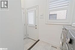 Doorway to outside with separate washer and dryer and light tile patterned flooring - 