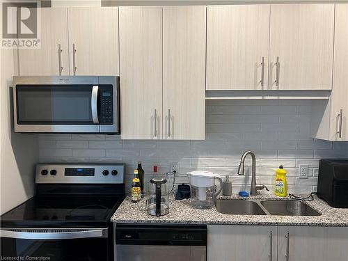 Kitchen featuring stainless steel appliances, light brown cabinetry, sink, and light stone countertops - 104 Garment Street Unit# 1608, Kitchener, ON - Indoor Photo Showing Kitchen With Double Sink With Upgraded Kitchen