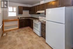 Unit 56 Kitchen featuring white appliances, dark brown cabinetry, and sink - 