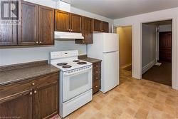 Unit 56 Kitchen featuring dark brown cabinets and white appliances - 