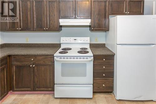 Unit 56 Kitchen featuring dark brown cabinetry and white appliances - 60 Wellington St N/S Street N, Woodstock, ON - Indoor Photo Showing Kitchen