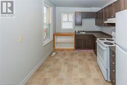 Unit 56 Kitchen featuring dark brown cabinetry, sink, and white appliances - 