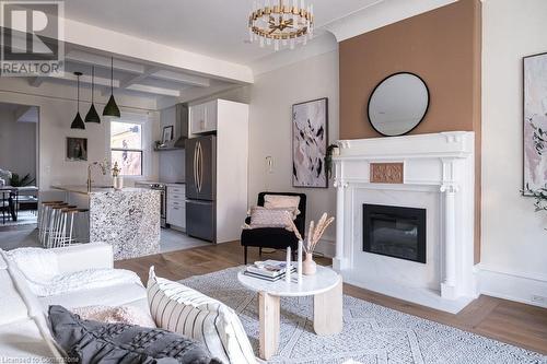 Living room with coffered ceiling, sink, beam ceiling, a notable chandelier, and light hardwood / wood-style floors - 109 East Avenue S, Hamilton, ON - Indoor Photo Showing Living Room With Fireplace