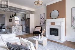 Living room with coffered ceiling, sink, beam ceiling, a notable chandelier, and light hardwood / wood-style floors - 