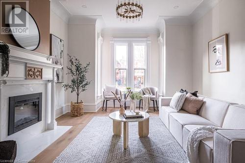 Living room featuring a high end fireplace, light hardwood / wood-style floors, and ornamental molding - 109 East Avenue S, Hamilton, ON - Indoor Photo Showing Living Room With Fireplace