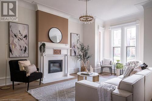 Living room with light hardwood / wood-style flooring and a notable chandelier - 109 East Avenue S, Hamilton, ON - Indoor Photo Showing Living Room With Fireplace