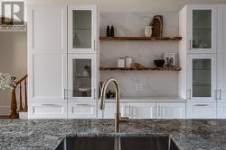 Kitchen with white cabinets, light stone countertops, sink, and tasteful backsplash - 