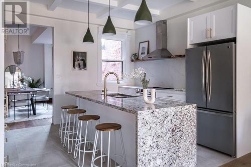 Kitchen with ventilation hood, decorative backsplash, appliances with stainless steel finishes, beam ceiling, and white cabinetry - 109 East Avenue S, Hamilton, ON - Indoor Photo Showing Kitchen With Double Sink With Upgraded Kitchen