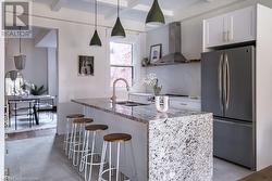 Kitchen with ventilation hood, decorative backsplash, appliances with stainless steel finishes, beam ceiling, and white cabinetry - 