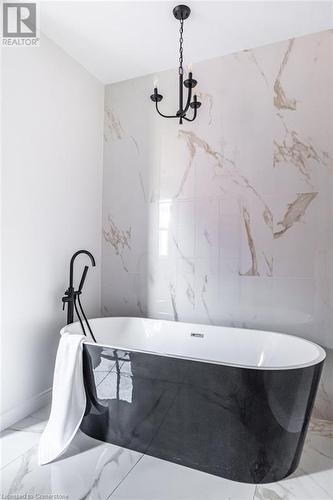 Bathroom featuring a tub and a notable chandelier - 109 East Avenue S, Hamilton, ON - Indoor Photo Showing Bathroom