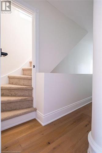 Staircase with hardwood / wood-style floors and ornate columns - 109 East Avenue S, Hamilton, ON - Indoor Photo Showing Other Room