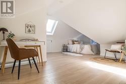 Bedroom with lofted ceiling with skylight and light hardwood / wood-style floors - 