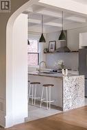 Kitchen featuring white cabinetry, pendant lighting, decorative backsplash, island range hood, and light wood-type flooring - 