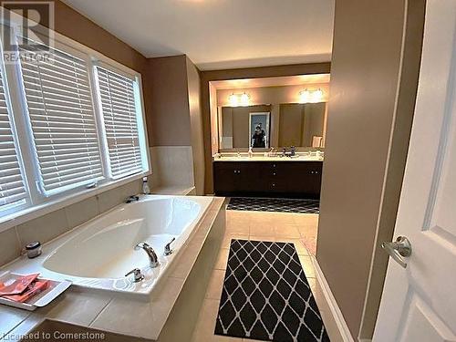 Bathroom featuring vanity, a relaxing tiled tub, and tile patterned floors - 906 Farmstead Drive, Milton, ON - Indoor Photo Showing Bathroom