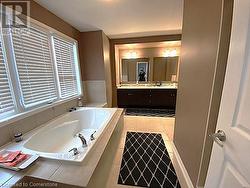 Bathroom featuring vanity, a relaxing tiled tub, and tile patterned floors - 