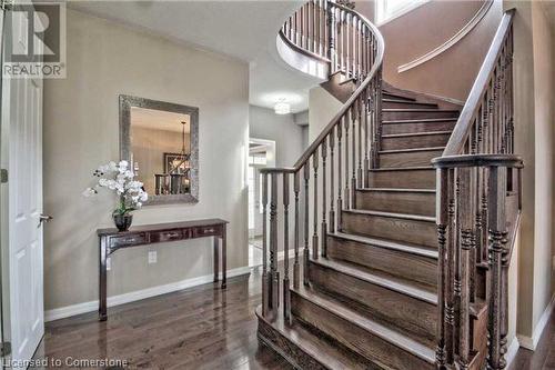 Staircase with hardwood / wood-style floors and an inviting chandelier - 906 Farmstead Drive, Milton, ON - Indoor Photo Showing Other Room