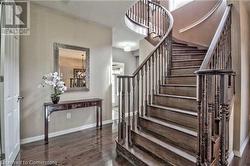 Staircase with hardwood / wood-style floors and an inviting chandelier - 