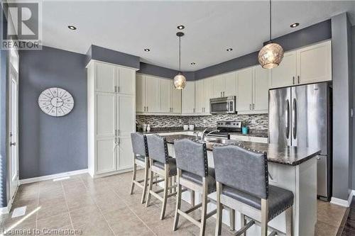 Kitchen with decorative backsplash, a kitchen island with sink, pendant lighting, and appliances with stainless steel finishes - 906 Farmstead Drive, Milton, ON - Indoor Photo Showing Kitchen With Upgraded Kitchen