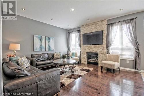 Living room with a fireplace, plenty of natural light, and hardwood / wood-style flooring - 906 Farmstead Drive, Milton, ON - Indoor Photo Showing Living Room With Fireplace