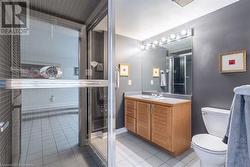 Bathroom featuring toilet, vanity, tile patterned floors, and an enclosed shower - 