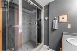 Bathroom featuring tile patterned floors, a shower with door, and sink - 