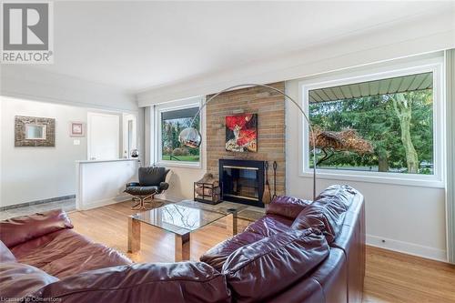 Living room with a brick fireplace, a wealth of natural light, and light wood-type flooring - 103 Mcgregor Crescent, Ancaster, ON - Indoor Photo Showing Living Room With Fireplace