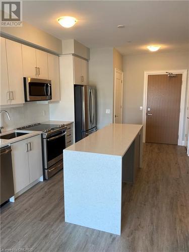 Kitchen with backsplash, stainless steel appliances, sink, hardwood / wood-style flooring, and a center island - 128 Grovewood Common Unit# 117, Oakville, ON - Indoor Photo Showing Kitchen With Stainless Steel Kitchen With Upgraded Kitchen