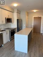 Kitchen with backsplash, stainless steel appliances, sink, hardwood / wood-style flooring, and a center island - 