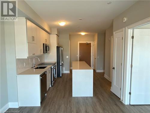 Kitchen featuring white cabinets, appliances with stainless steel finishes, dark hardwood / wood-style floors, and tasteful backsplash - 128 Grovewood Common Unit# 117, Oakville, ON - Indoor Photo Showing Kitchen With Upgraded Kitchen