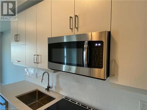 Details featuring decorative backsplash, sink, and white cabinets - 128 Grovewood Common Unit# 117, Oakville, ON - Indoor Photo Showing Kitchen With Double Sink