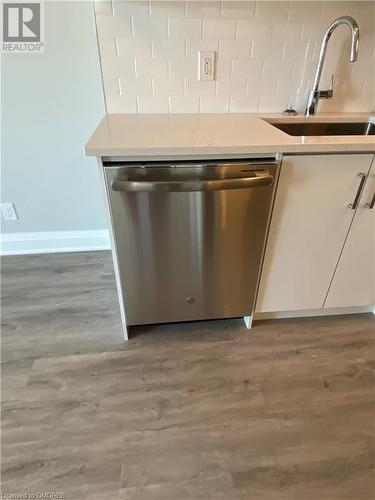 Kitchen with hardwood / wood-style flooring, dishwasher, white cabinetry, and sink - 128 Grovewood Common Unit# 117, Oakville, ON - Indoor Photo Showing Kitchen