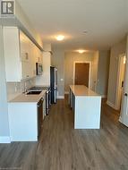 Kitchen with white cabinetry, sink, stainless steel appliances, tasteful backsplash, and hardwood / wood-style floors - 