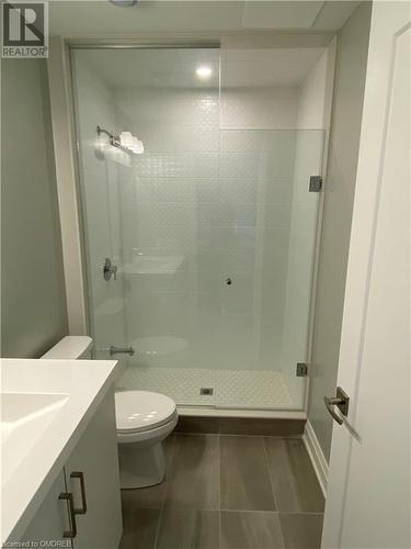 Bathroom featuring tile patterned flooring, vanity, toilet, and a shower with door - 128 Grovewood Common Unit# 117, Oakville, ON - Indoor Photo Showing Bathroom