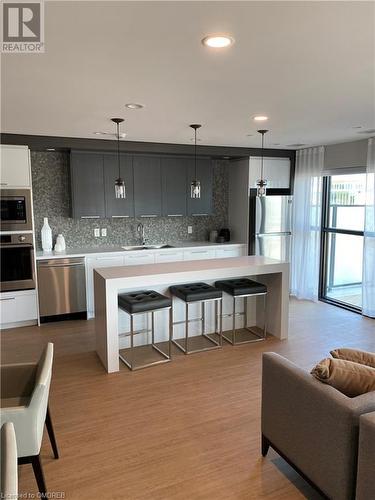 Kitchen featuring pendant lighting, sink, light wood-type flooring, appliances with stainless steel finishes, and tasteful backsplash - 128 Grovewood Common Unit# 117, Oakville, ON - Indoor Photo Showing Kitchen With Stainless Steel Kitchen With Upgraded Kitchen