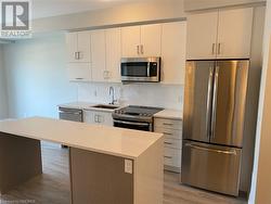 Kitchen featuring sink, light hardwood / wood-style flooring, a kitchen island, and appliances with stainless steel finishes - 