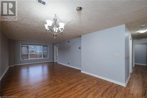 Spare room featuring dark hardwood / wood-style flooring, a textured ceiling, and an inviting chandelier - 2555 3Rd 3Rd Avenue Avenue W Unit# 210, Owen Sound, ON - Indoor