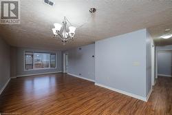 Spare room featuring dark hardwood / wood-style flooring, a textured ceiling, and an inviting chandelier - 