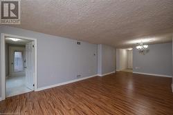 Unfurnished room featuring wood-type flooring, a textured ceiling, and an inviting chandelier - 