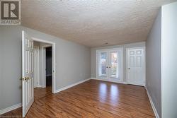 Spare room featuring wood-type flooring, a textured ceiling, and french doors - 