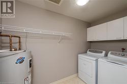 Laundry room featuring cabinets, electric water heater, and separate washer and dryer - 