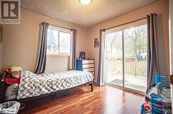 Bedroom with access to exterior, hardwood / wood-style floors, and a textured ceiling - 