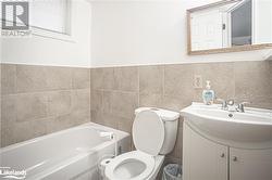 Bathroom featuring a washtub, vanity, tile walls, and toilet - 