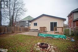 Rear view of house with a wooden deck, a yard, and a fire pit - 