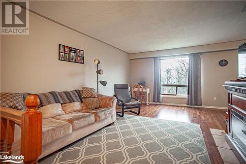 Living room featuring wood-type flooring and a textured ceiling - 96 Sixth Street, Midland, ON - Indoor Photo Showing Living Room With Fireplace